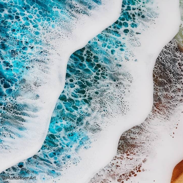 Close-up of ocean wave art with white foam and vibrant blue-green tones in abstract resin or alcohol ink style